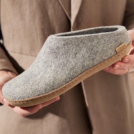 Person holding a par of grey leather sole slippers in closeup